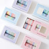 A collection of colorful washi tape rolls in various shades and patterns displayed in individual packaging.