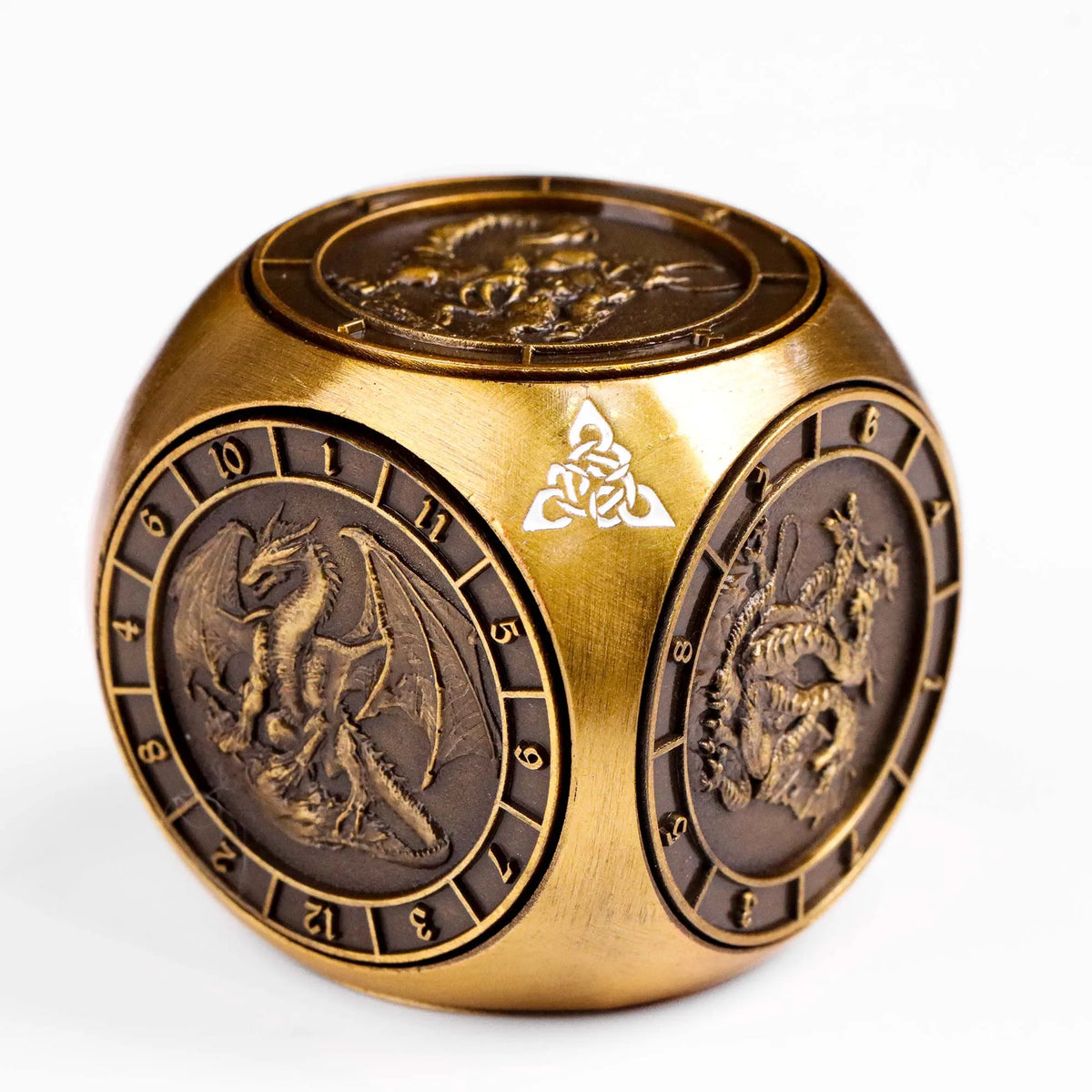 A gold metal spinner dice cube featuring embossed designs and a carved symbol.