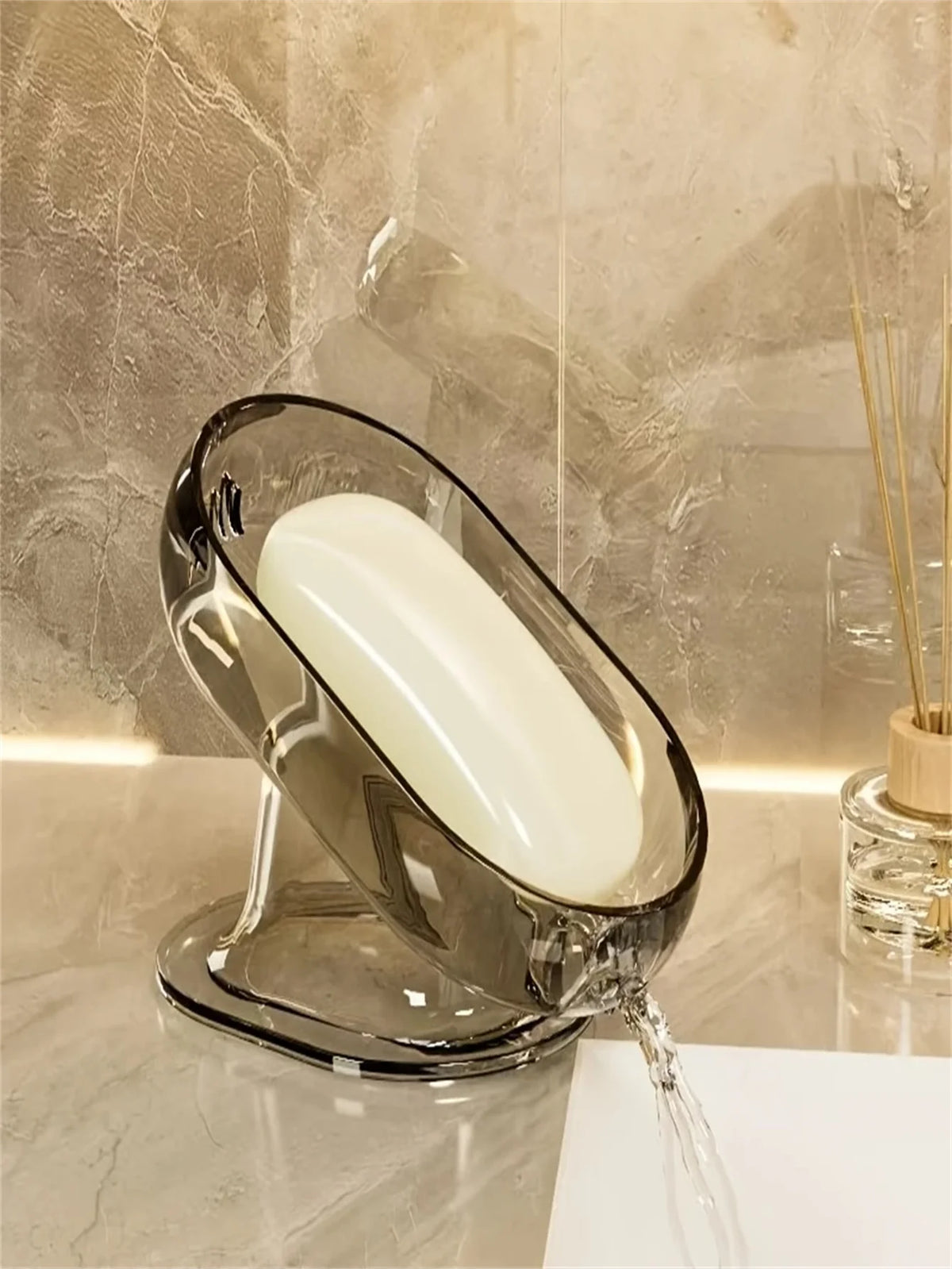 Elegisches Glasseifschale mit einer weißen Seife tropft Wasser auf eine Marmoroberfläche.