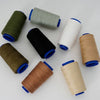 A collection of spools of heavy-duty polyester thread in various colors including olive green, gray, black, white, and tan.
