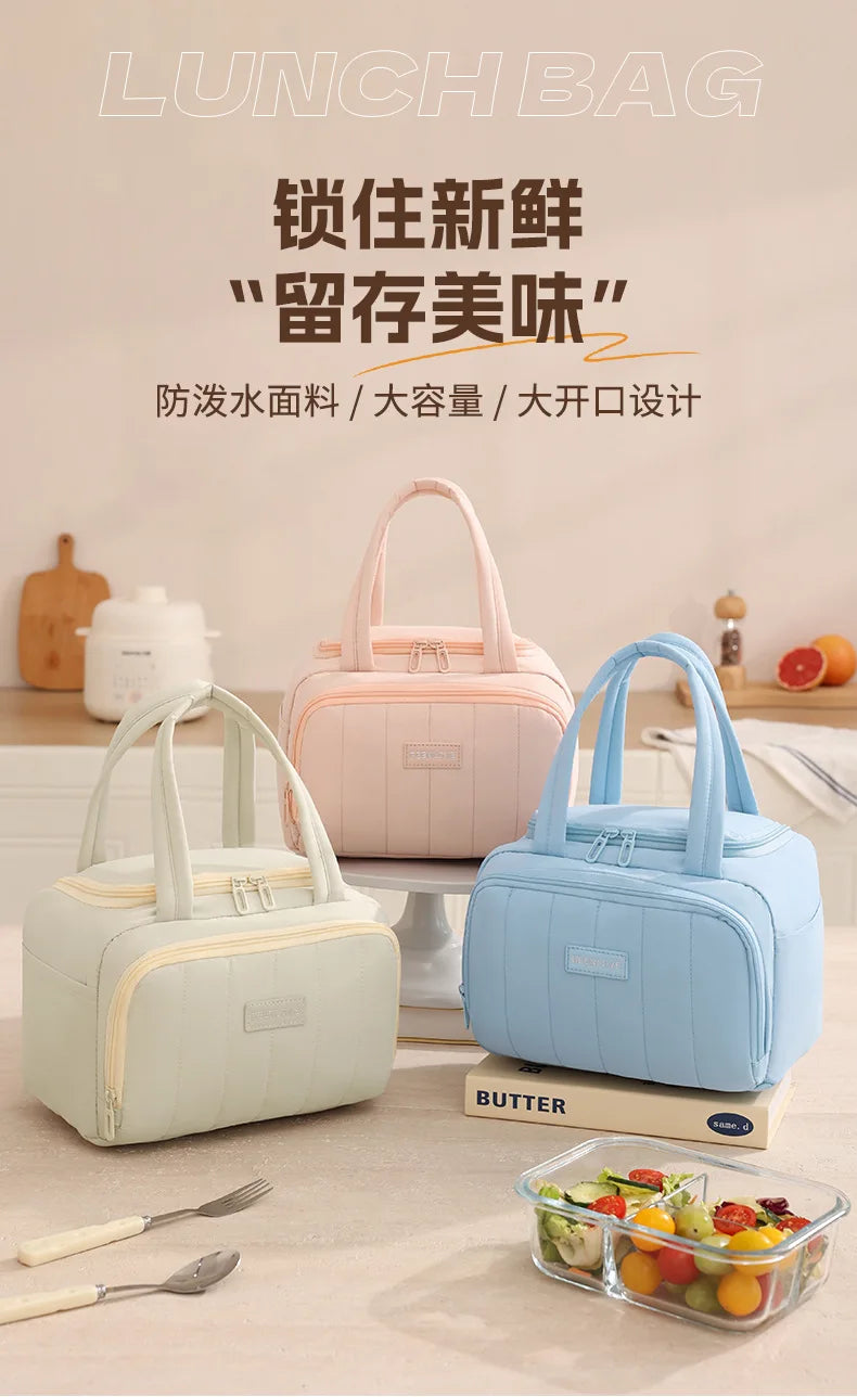 A light pink and blue insulated quilted lunch bag is displayed next to a sliced fruit container.