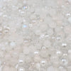 A close-up view of mixed sizes clear and milky white glass beads for jewelry making.