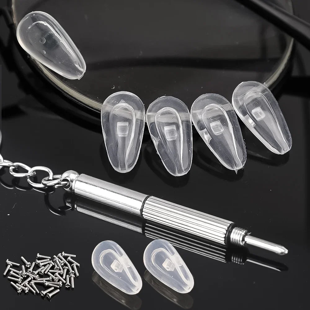 A set of clear silicone nose pads and a mini screwdriver for glasses repair displayed on a dark surface.