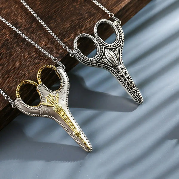 A pair of vintage stainless steel sewing scissors with gold accents hanging from a silver chain.