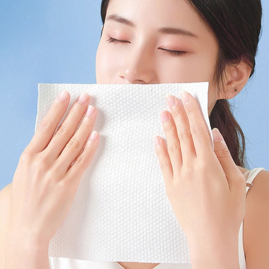 Una mujer usa una toalla desechable blanca y gruesa para secarse la cara.