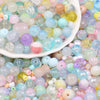 A close-up view of mixed sizes and colors of clear, iridescent glass beads for jewelry making.