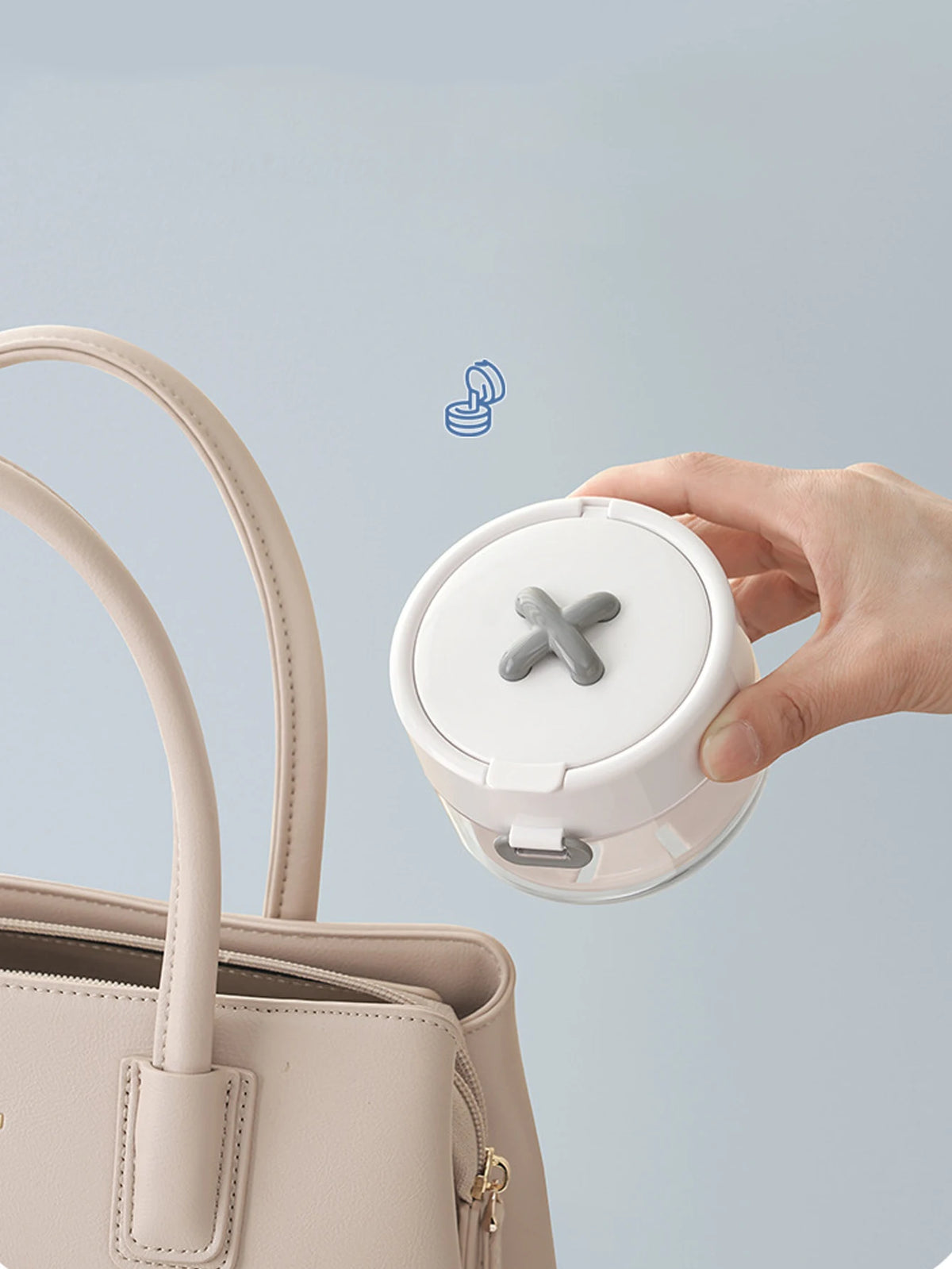 A hand holds a white portable denture case with a cleaning brush storage feature, next to a light pink handbag.