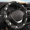 A black steering wheel with a skull and rose pattern cover installed in a car interior.