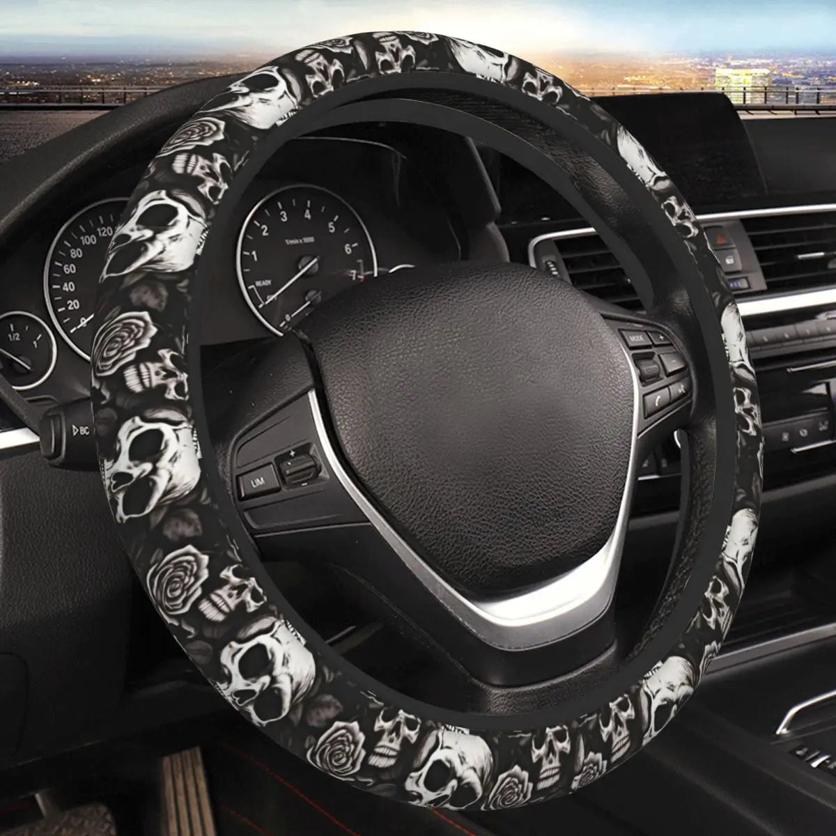 A black steering wheel with a skull and rose pattern cover installed in a car interior.