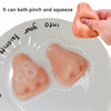 A pink squishy pimple popper fidget toy is shown being pinched and squeezed on a white plate.