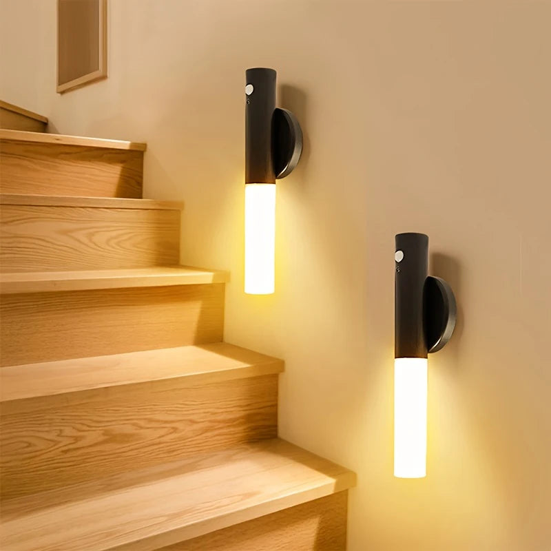 A magnetic LED wall light with a motion sensor mounted on a beige wall next to wooden stairs.