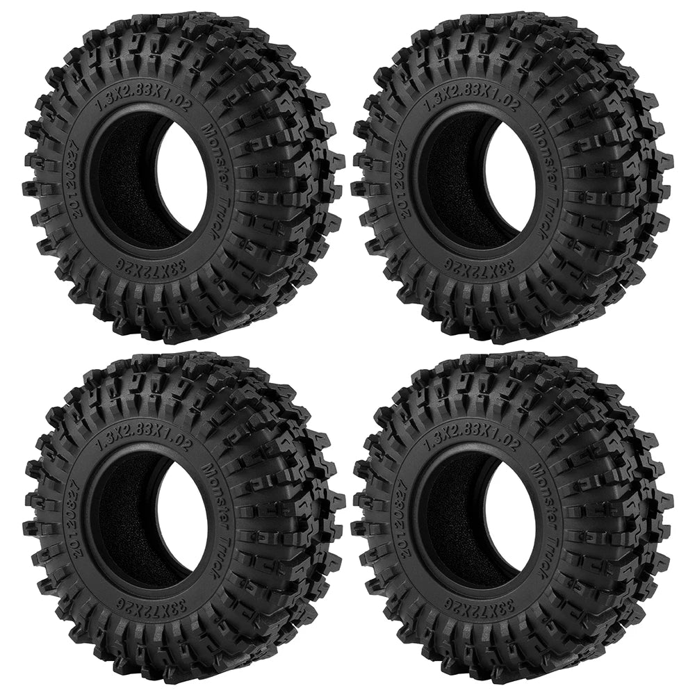 A set of four black mud terrain rubber tires for RC crawlers, showing the tread pattern and mounting holes.
