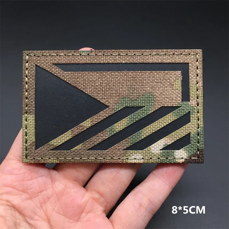 A rectangular tactical patch featuring a camouflage pattern with a triangular design and hook-and-loop backing.