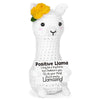 A white crochet llama doll with a yellow flower on its head and a positive message card attached.