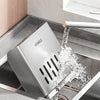 A stainless steel cutlery organizer with a detachable drain tray is shown being used to rinse cutlery.