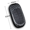 A black carbon fiber key fob cover with panic and lock buttons shown next to a measurement scale.