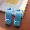 A pair of light blue universal car seat headrest hooks resting on a white book.