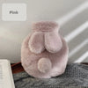 A fluffy pink plush rabbit hot water bottle with a soft flannel cover resting on a gray textured surface.