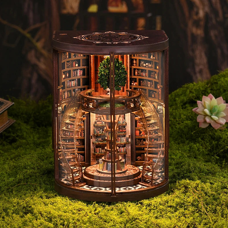 A miniature DIY wooden book nook kit featuring detailed bookshelves and a small tree, set in a natural mossy environment.