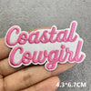 Pink embroidered patch with the text Coastal Cowgirl on a hand