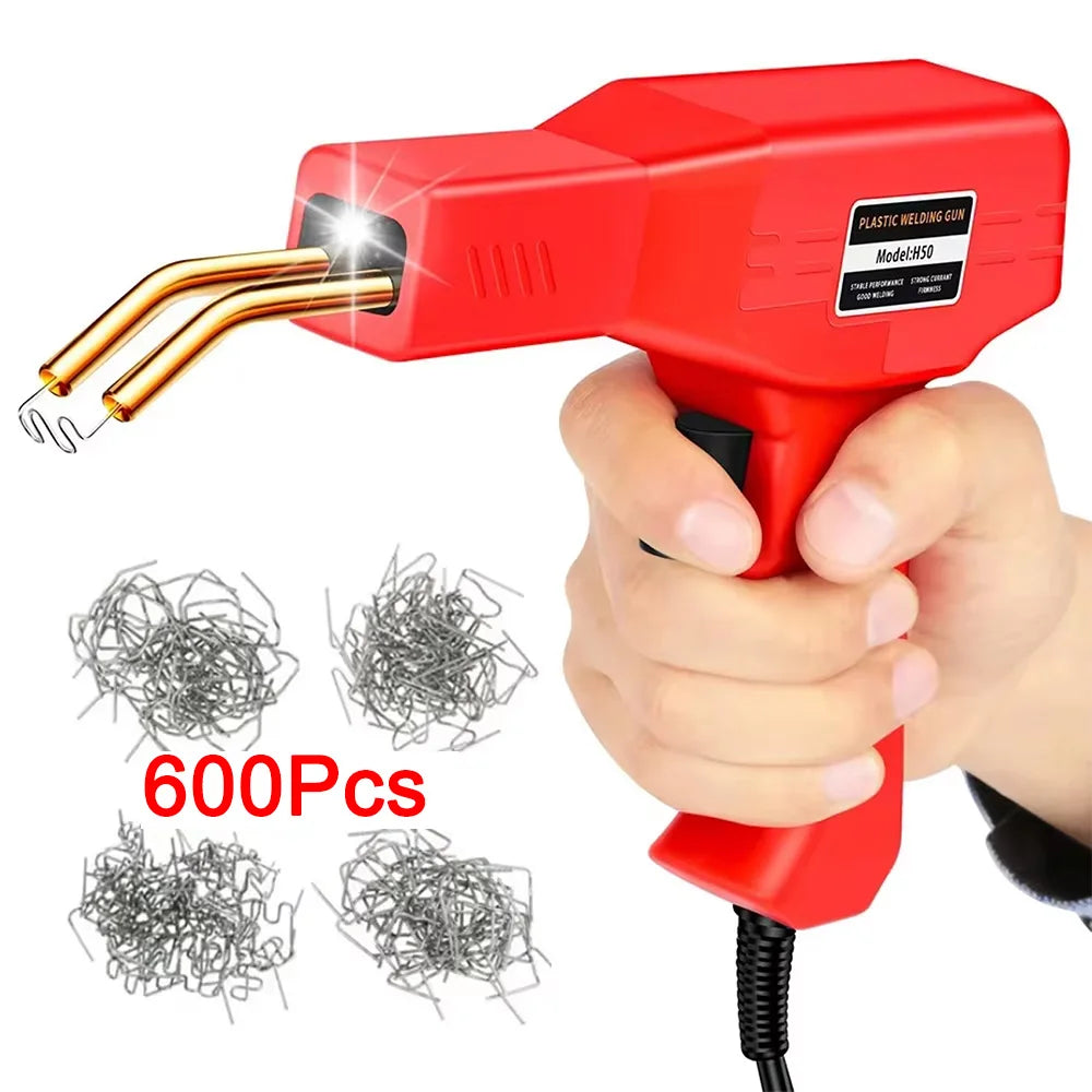 A hand holds a red plastic welding gun with a gold tip, next to several packs of metal wire.