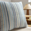 A close-up of a light blue and white patterned linen pillow cover with blue geometric designs.