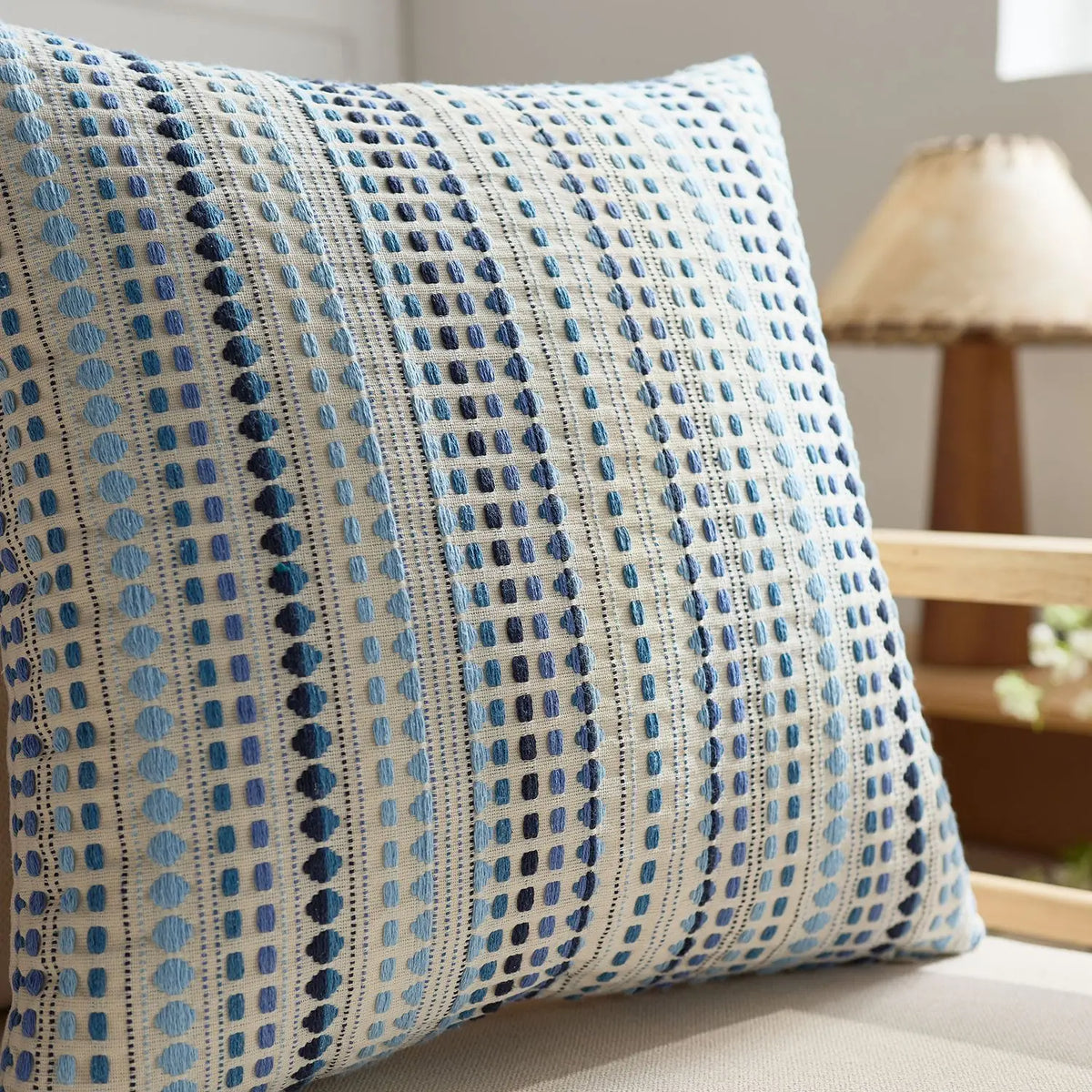 A close-up of a light blue and white patterned linen pillow cover with blue geometric designs.