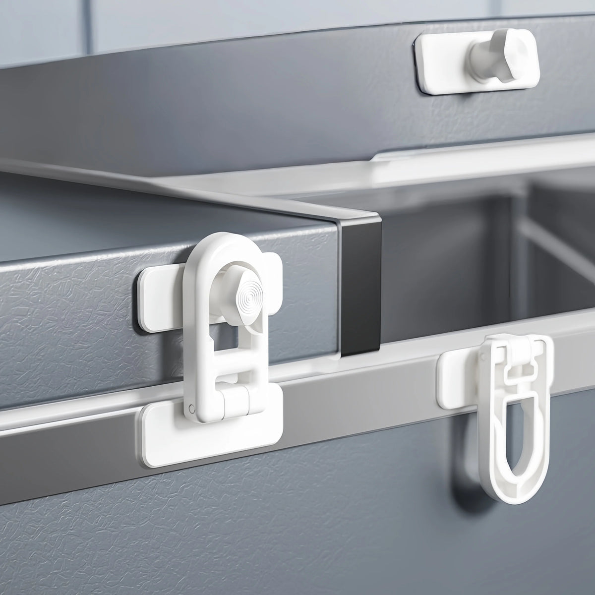 Close-up of a silver appliance door with white non-drill child safety locks installed.