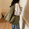 A person is holding a large olive green lightweight nylon tote bag with a secure zipper closure.