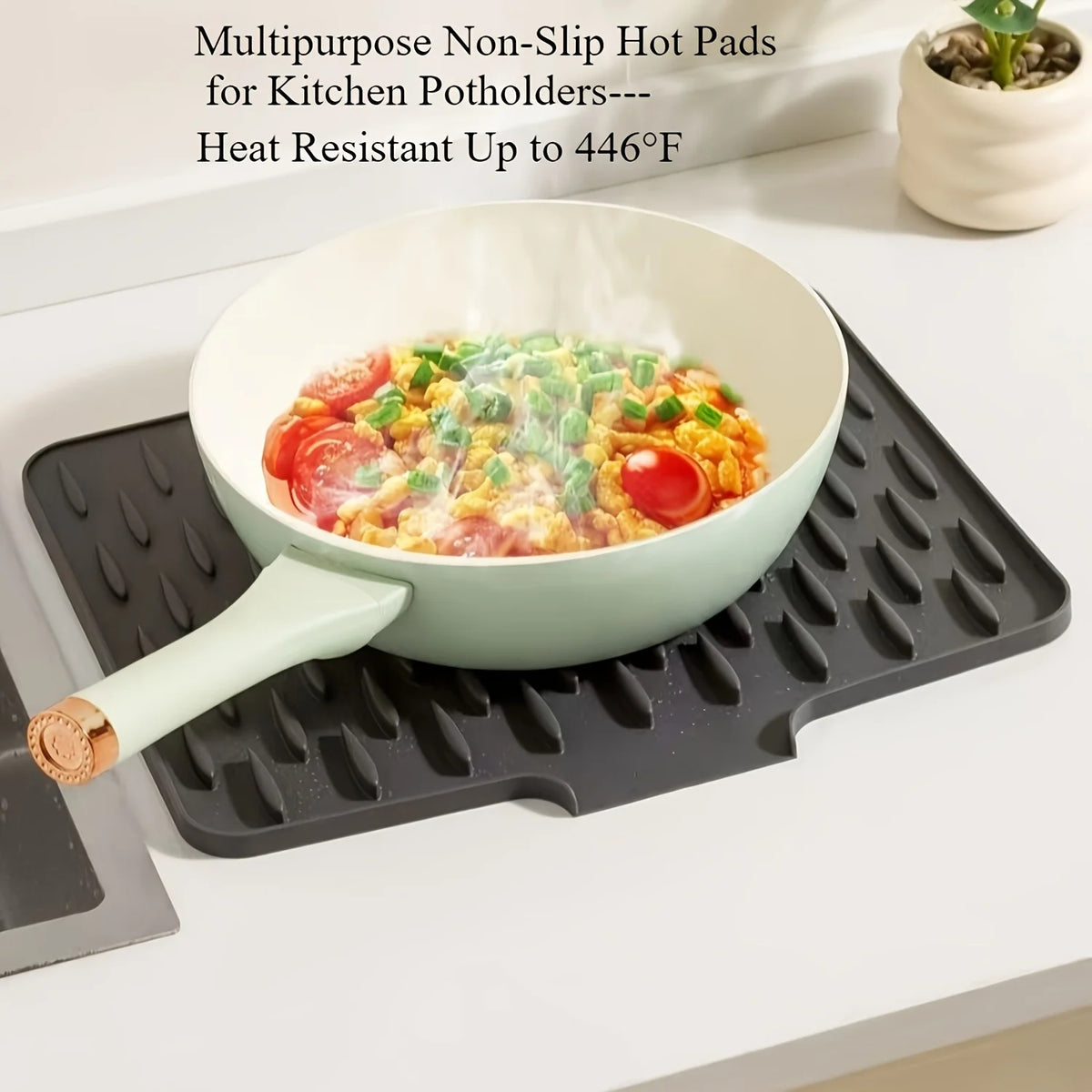 A light green bowl of food is sitting on a black silicone dish drying mat with a white silicone spatula.
