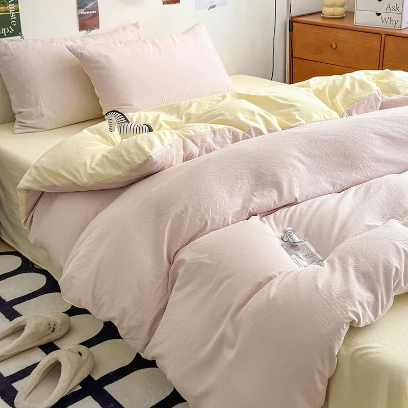 A bed with a pink duvet cover set featuring light pink and cream colored bedding and pillows.