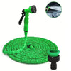 A bright green expandable magic hose with a nozzle and spray patterns resting on a surface.