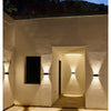 A white stucco wall features several upward-pointing LED lights illuminating an entryway.