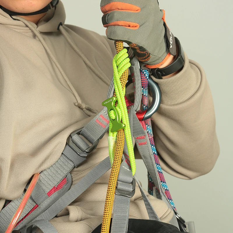A person wearing a hoodie is adjusting a durable auxiliary rope for climbing and descent safety.