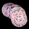 A stack of pink and purple ruffled waterproof shower caps for bathing and hair care.