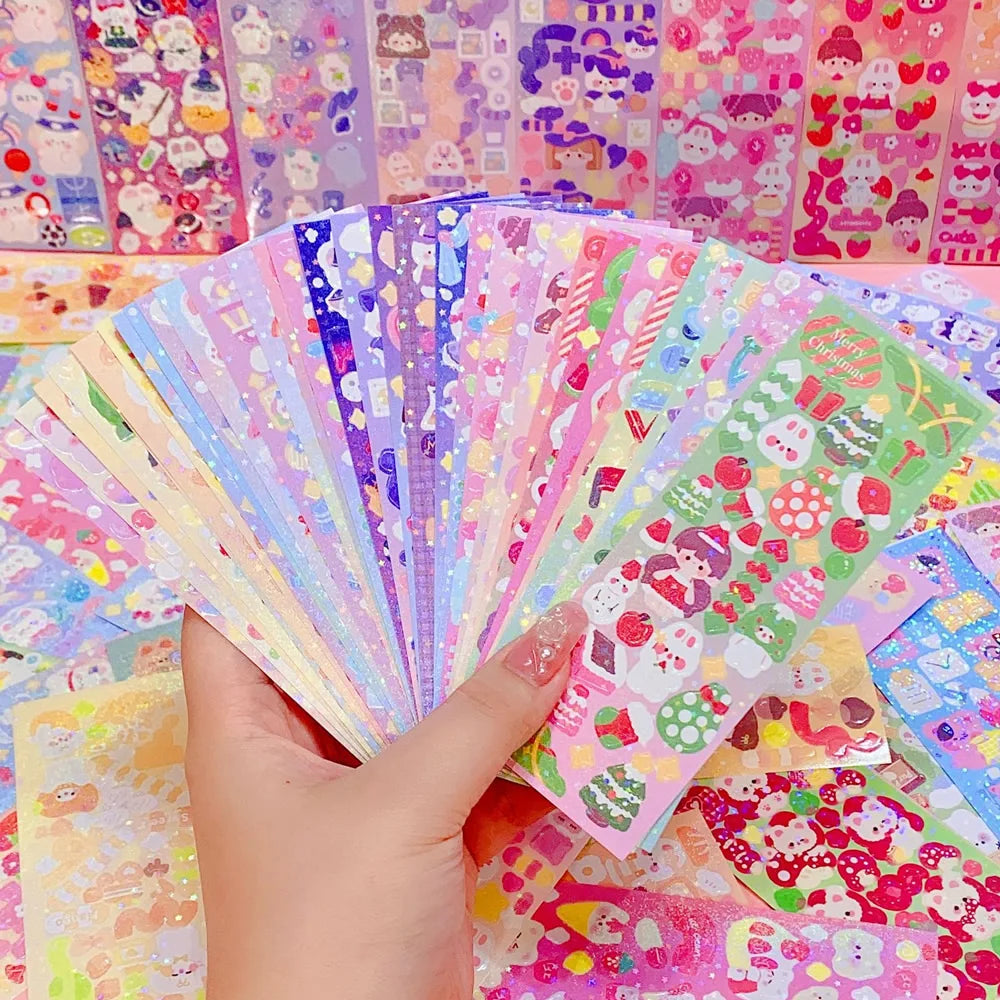 A hand holds a fan of colorful kawaii stickers for journaling and crafts.