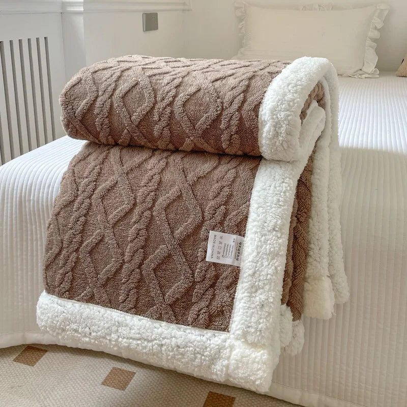 A brown and white double-layer fleece throw blanket folded on a white bed with a white textured cover.