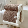 A brown and white double-layer fleece throw blanket folded on a white bed with a white textured cover.