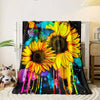 A vibrant floral print blanket featuring large yellow sunflowers and colorful paint splatters on a black background.