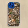 A silicone phone case with a forest camouflage pattern featuring tree branches and autumn leaves.