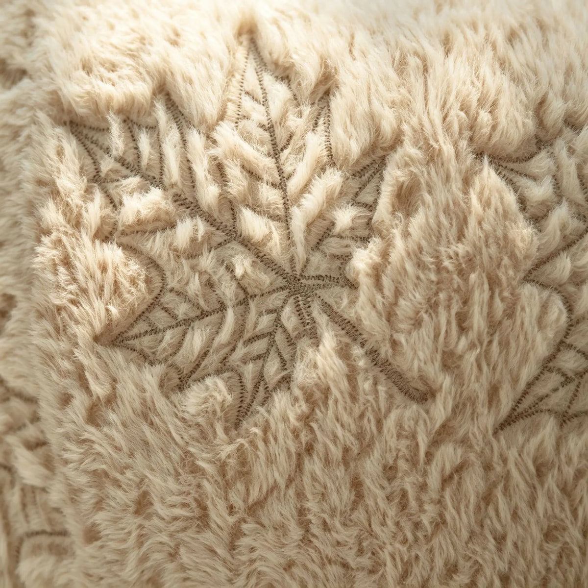 Close-up of a beige faux fur throw pillow cover featuring an embroidered maple leaf pattern.
