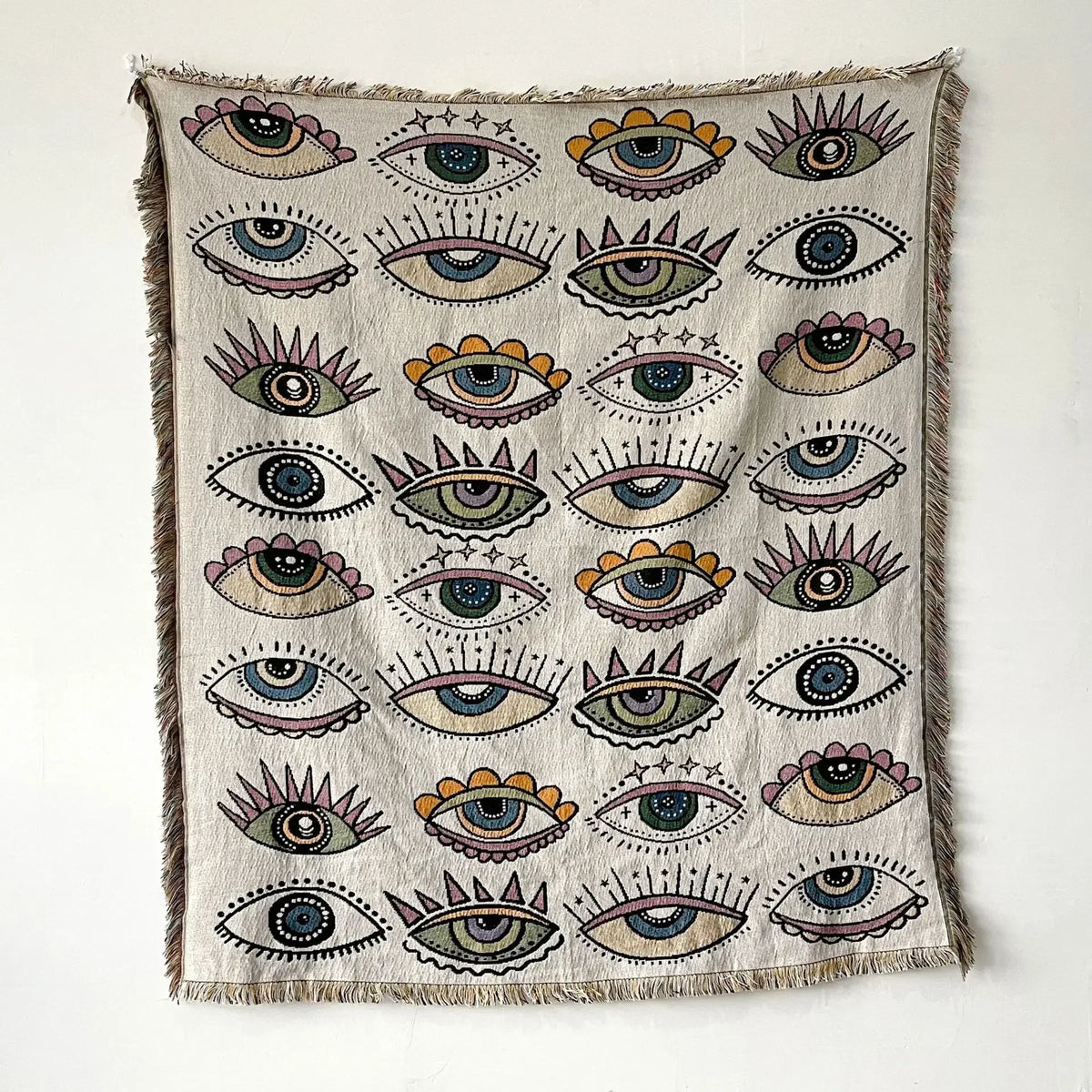 A woven throw blanket featuring a pattern of stylized eyes in various colors and shades.