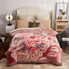 A pink and red floral weighted blanket is displayed on a bed with white bedding and wooden furniture.