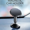 A black magnetic car holder with a double 360 degree rotating ball mounted on a car dashboard.