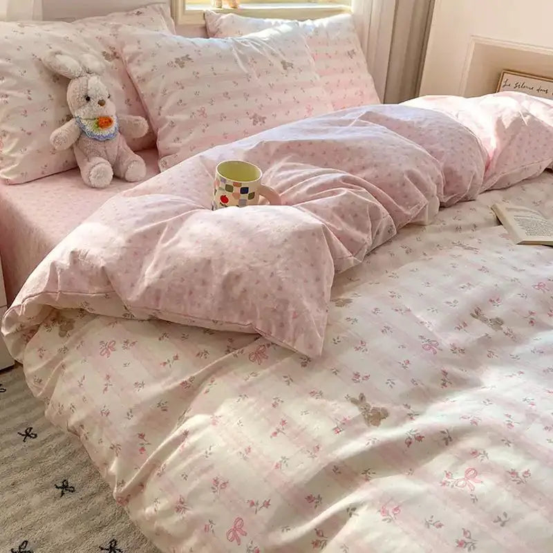 Pink floral bedding set featuring a duvet cover, pillows, and a stuffed rabbit toy.