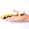 A hand holds several realistic animal figurines, including a white goose and yellow chicks, on a white background.