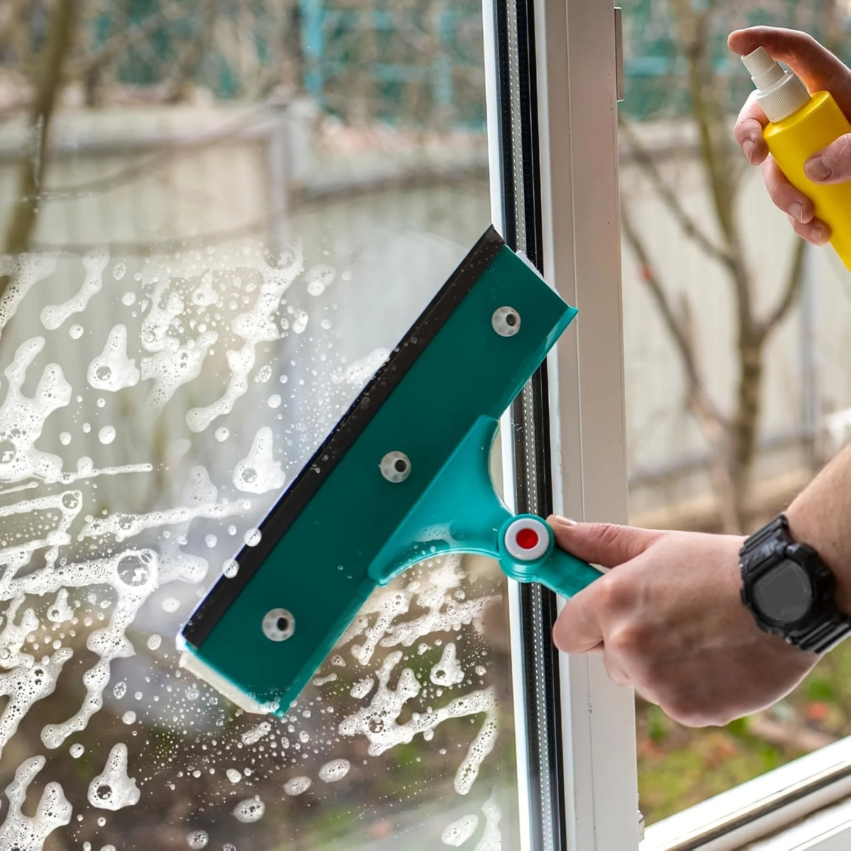 A hand is using a teal squeegee replacement rubber blade to clean condensation and water spots on a window.