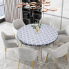 A round table set featuring a gray patterned tablecloth, modern chairs, and black shelving.