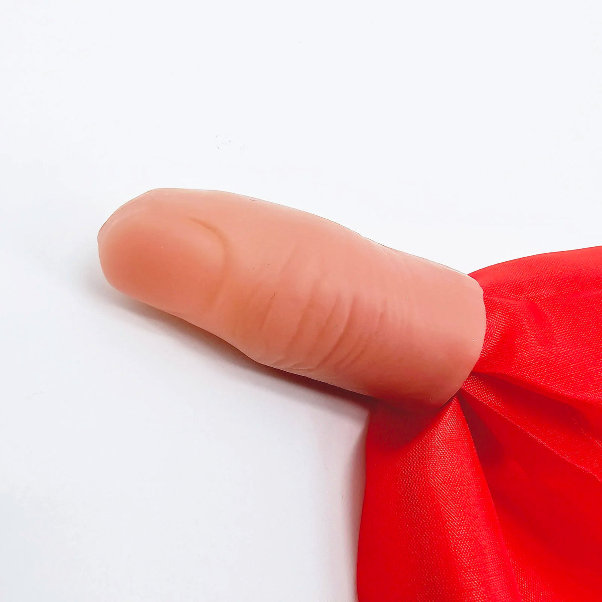 A close-up of a hand with a thumb tip, showing the classic magic thumb tip with vanishing silk.