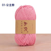 A pink ball of cotton blend crochet yarn is shown on a wooden surface.